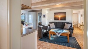 Ein Wohnzimmer mit einer Couch, einem Couchtisch und einem Gemälde vom Sonnenuntergang.