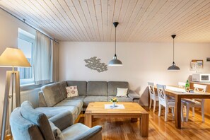 Un soggiorno moderno con divano, tavolino in legno e zona pranzo con sedie e tavolo.
