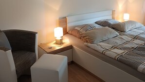 Ein Schlafzimmer mit Bett, Nachttischen, einem Sessel und einem Wandbild.