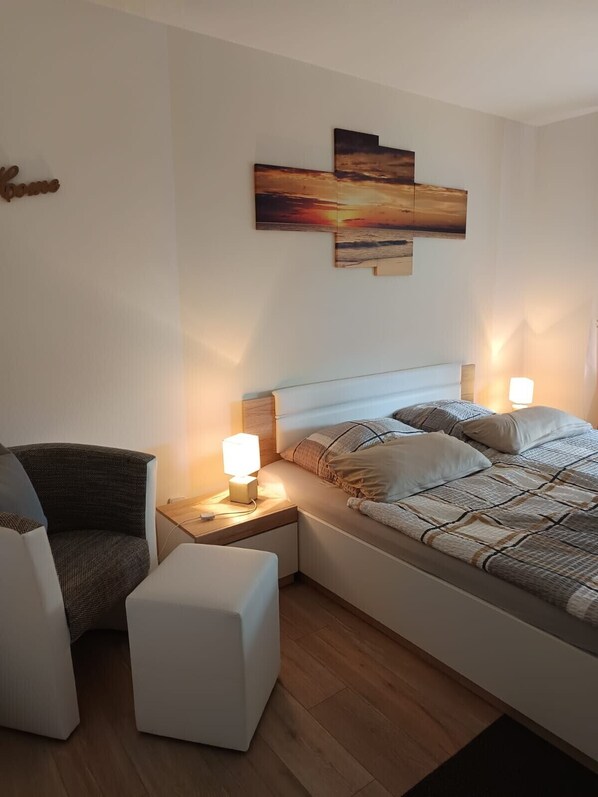 A bedroom with a bed, bedside tables, a chair, and a wall-mounted artwork.