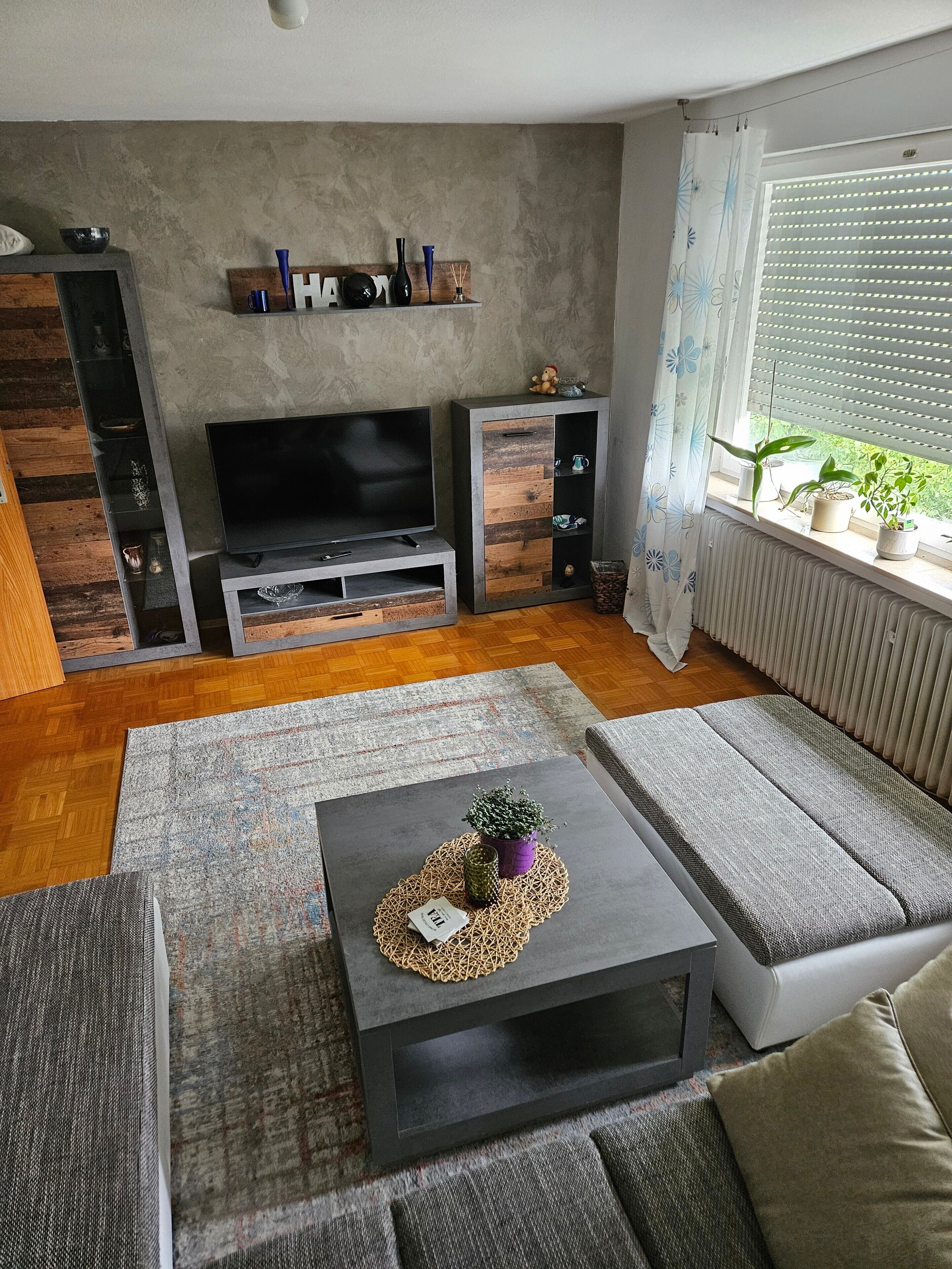 Una sala de estar con televisor, sofá, mesa de centro y objetos decorativos.