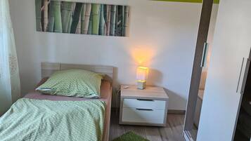 Une chambre à coucher avec un lit, une table de chevet avec une lampe, une armoire et un tapis vert.
