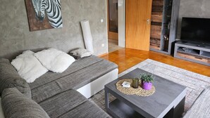 Ein modernes Wohnzimmer mit einer Couch, einem Couchtisch, einem Fernseher und einem Zebrabild an der Wand.