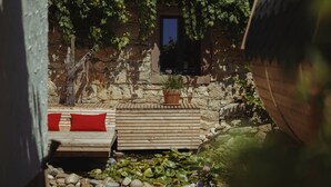 Un mur de pierre avec un banc en bois et un pot de fleurs.