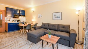 A modern living room with a grey sofa, a wooden coffee table, and a dining area with a table and chairs.