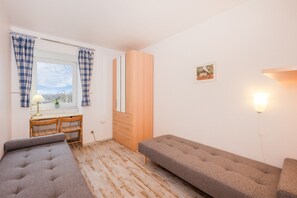 Ein Zimmer mit einem Bett, einem Schreibtisch, einem Kleiderschrank und einem Fenster mit Vorhängen.