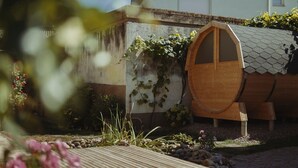 A rustic wooden barrel house with a sloped roof, surrounded by a garden with various plants and a wooden table. - Riesling Apartment with Shared Pool, Garden, and Wi-Fi (Auggen)