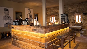 Un coin bar au décor rustique, avec des meubles en bois, des murs en pierre et un tableau affichant le menu.