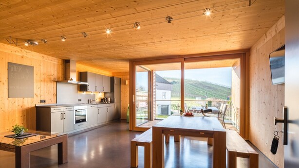 Une cuisine moderne avec des meubles en bois, une table à manger et une vue sur la campagne.