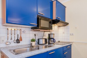 A kitchen with blue cabinets, a microwave, a toaster, and a coffee maker.