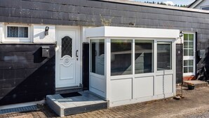 En moderne bygning med hvid dør, store vinduer og en lille veranda.