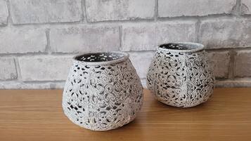 Two intricately patterned ceramic planters on a wooden surface against a brick wall.