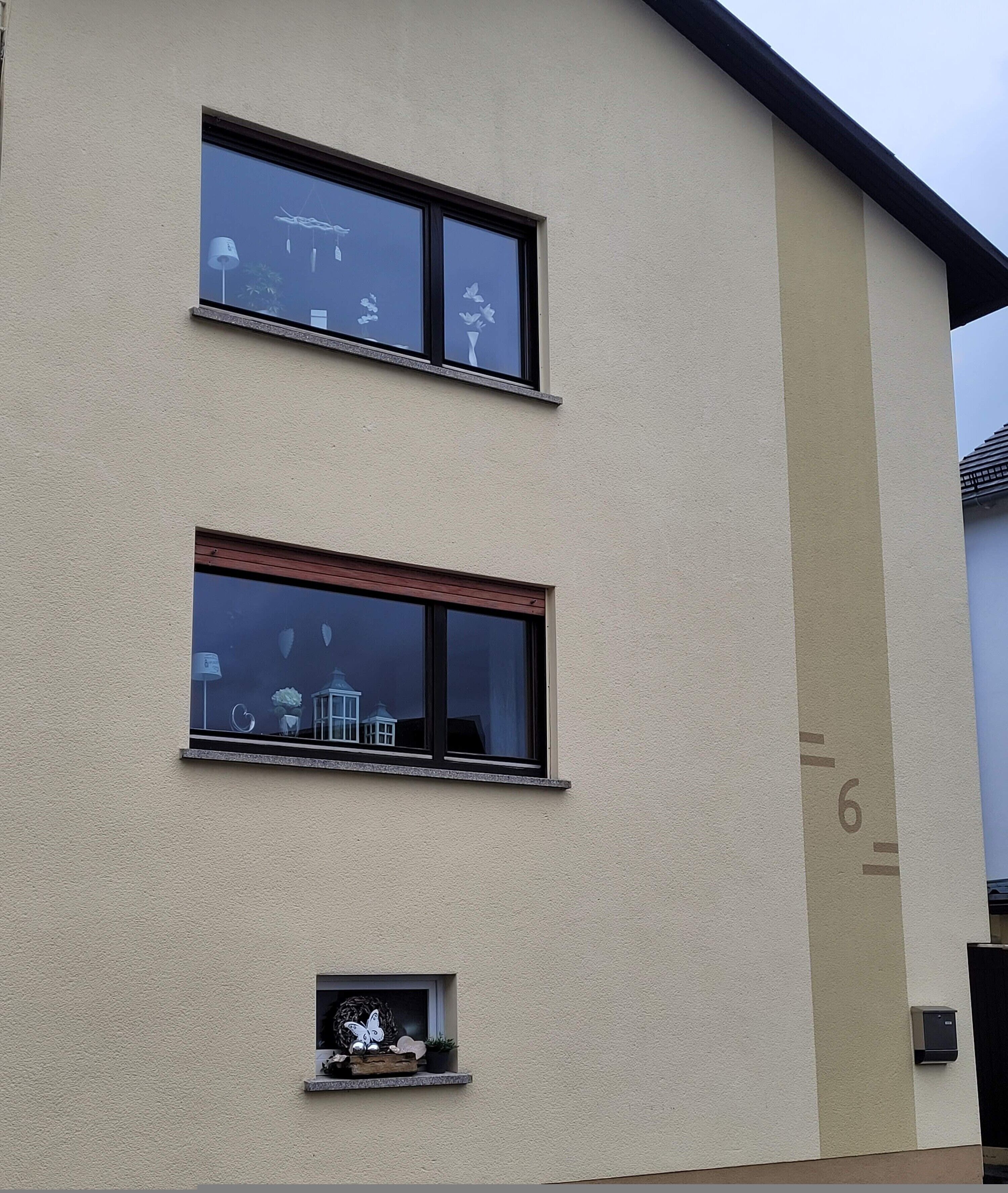 A building with two windows, a small balcony, and a number '6' on the wall.
