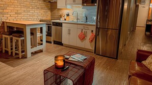 A modern kitchen with a brick wall, stainless steel appliances, and a dining area with a table and chairs.