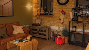 A cozy living room with a brick wall, a wooden ceiling, a clock, and a television.