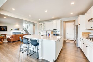 A spacious kitchen with white cabinetry, a large island, and modern appliances. - Berthoud Home w/ Fire Pit, Close to Lake Loveland! (Berthoud)