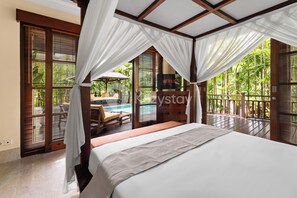 Une chambre avec un lit, des rideaux et une vue sur une piscine et une végétation tropicale.