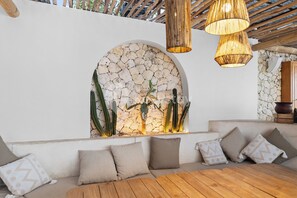 Un espace de vie moderne avec un mur en pierre, des meubles en bois et des luminaires suspendus.