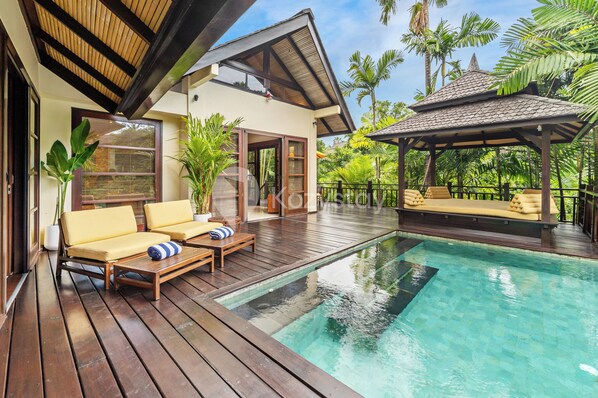 Une terrasse en bois avec une piscine, des chaises longues et un espace salon abrité.