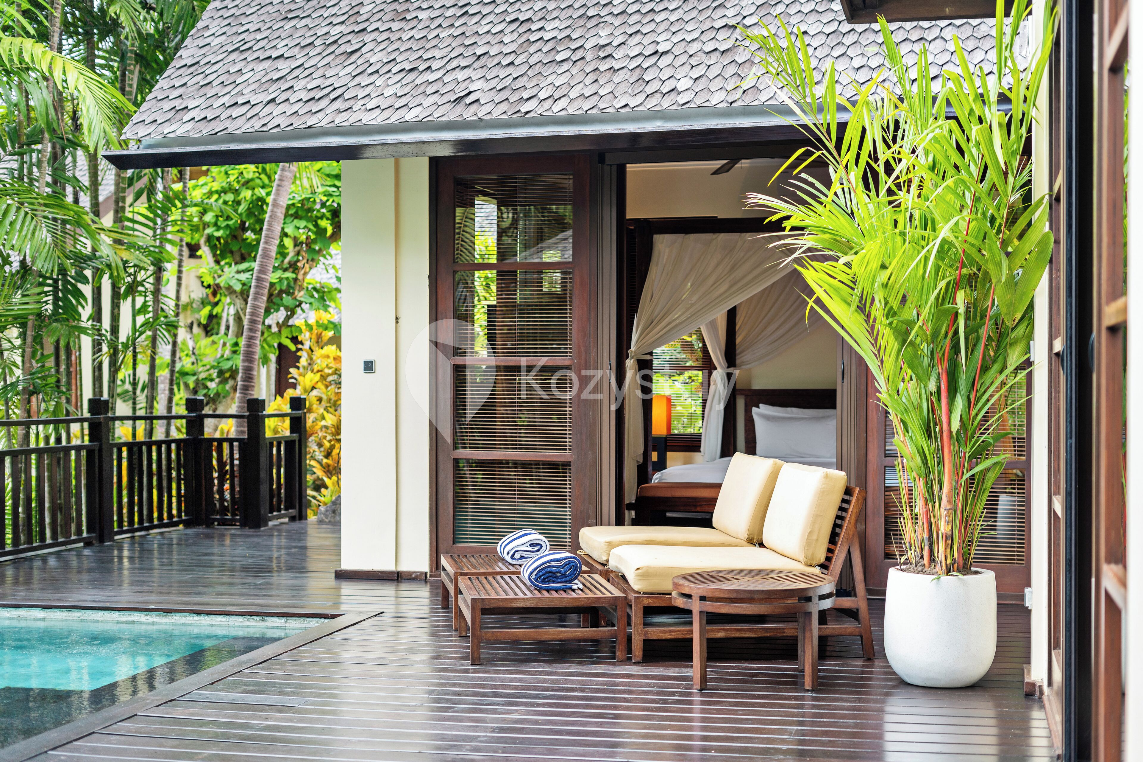 A poolside area with a lounge chair, a small table, and a potted plant.