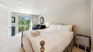 A bedroom with a large bed, a nightstand, a mirror, and a door leading to a balcony. - Forest Mtn Lodge: Hot Tub, Game Room, Near Trail (South Lake Tahoe)