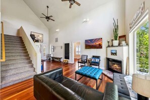 A spacious living area with a fireplace, a staircase, and a large window.