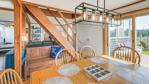Un espace repas comprenant une table en bois, des chaises et un escalier menant à un autre niveau.
