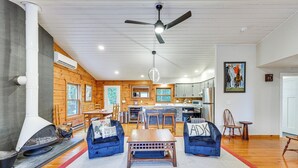 A modern living room with a fireplace, blue sofas, a wooden coffee table, and a ceiling fan. - Modern Cabin in Lake Placid w/ Mountain Views! (Lake Placid)