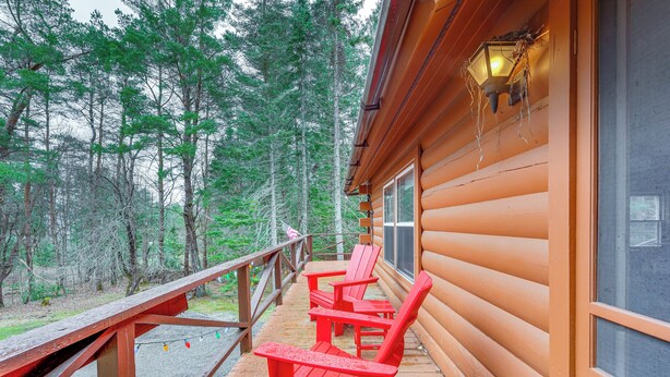 A wooden cabin with a deck featuring red Adirondack chairs and a wooden railing. - Modern Cabin in Lake Placid w/ Mountain Views! (Lake Placid)
