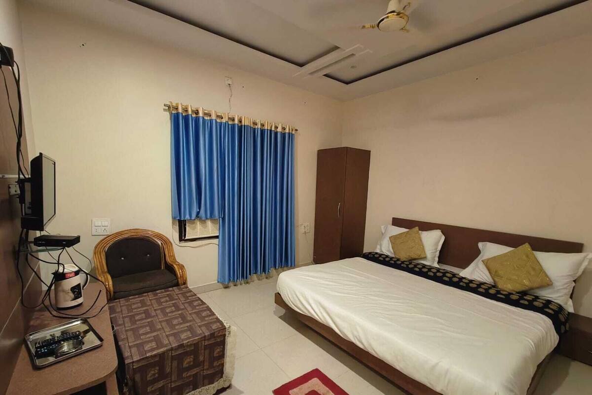 Ein Schlafzimmer mit Bett, Kleiderschrank, Schreibtisch mit Computer und Stuhl.