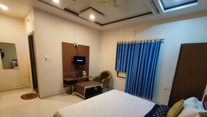 A bedroom with a bed, a television, a desk, and a chair. - Hotel Basant Palace (Gopadbanas)