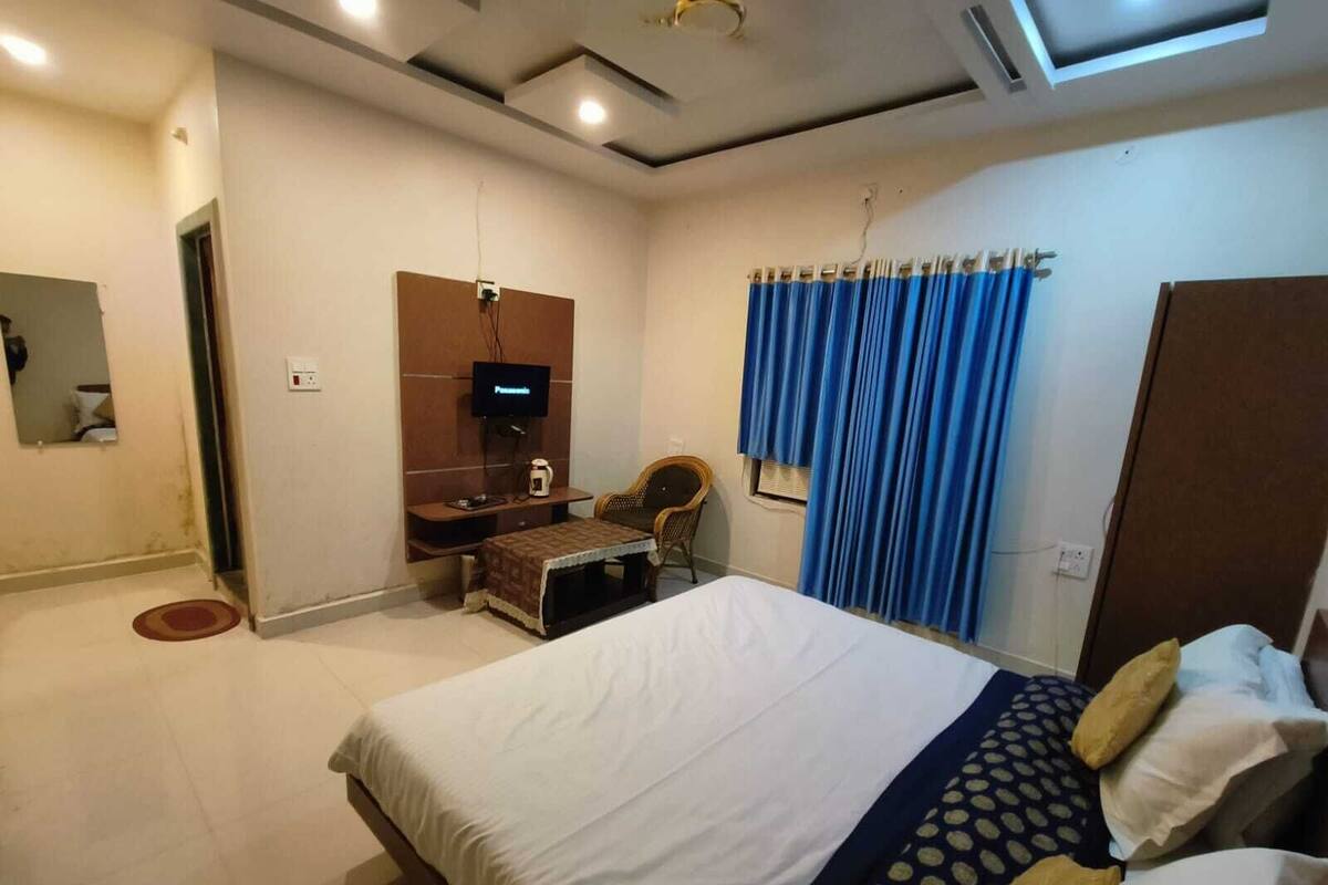 Ein Schlafzimmer mit einem Bett, einem Fernseher, einem Schreibtisch und einem Sessel.