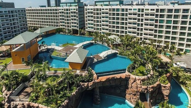 Et hotel med flere swimmingpools, klippeformation og palmer.