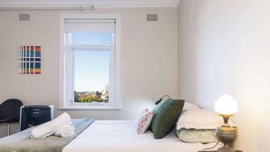 Ein Hotelzimmer mit Bett, Schreibtisch, Stuhl, Fenster mit Blick auf die Stadt und einer Lampe.