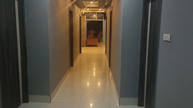 A hallway with a tiled floor, grey walls, and wooden doors. - HOTEL ROYAL RESIDENCY (Shillong)