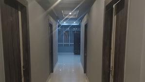 A hallway with a tiled floor, dark wooden doors, and recessed lighting. - HOTEL ROYAL RESIDENCY (Shillong)