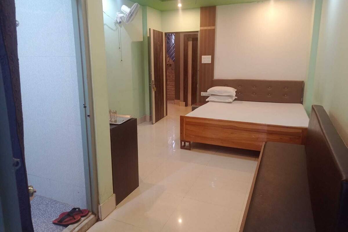 Un dormitorio con una cama de madera, un escritorio pequeño y una puerta que da a otra habitación.