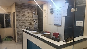 A reception desk with a stone wall, a clock, and a 'No Smoking' sign. - HOTEL ROYAL RESIDENCY (Shillong)