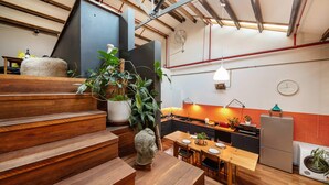 A modern kitchen with wooden countertops, a dining area with a wooden table and benches, and a staircase with a rustic design. - Spacious Warehouse Conversion, 2 Bdrms & Parking (Footscray)