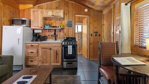 Une cuisine accueillante, aménagée dans le style d’un chalet, avec des meubles en bois, un four à micro-ondes, une cuisinière et un réfrigérateur.