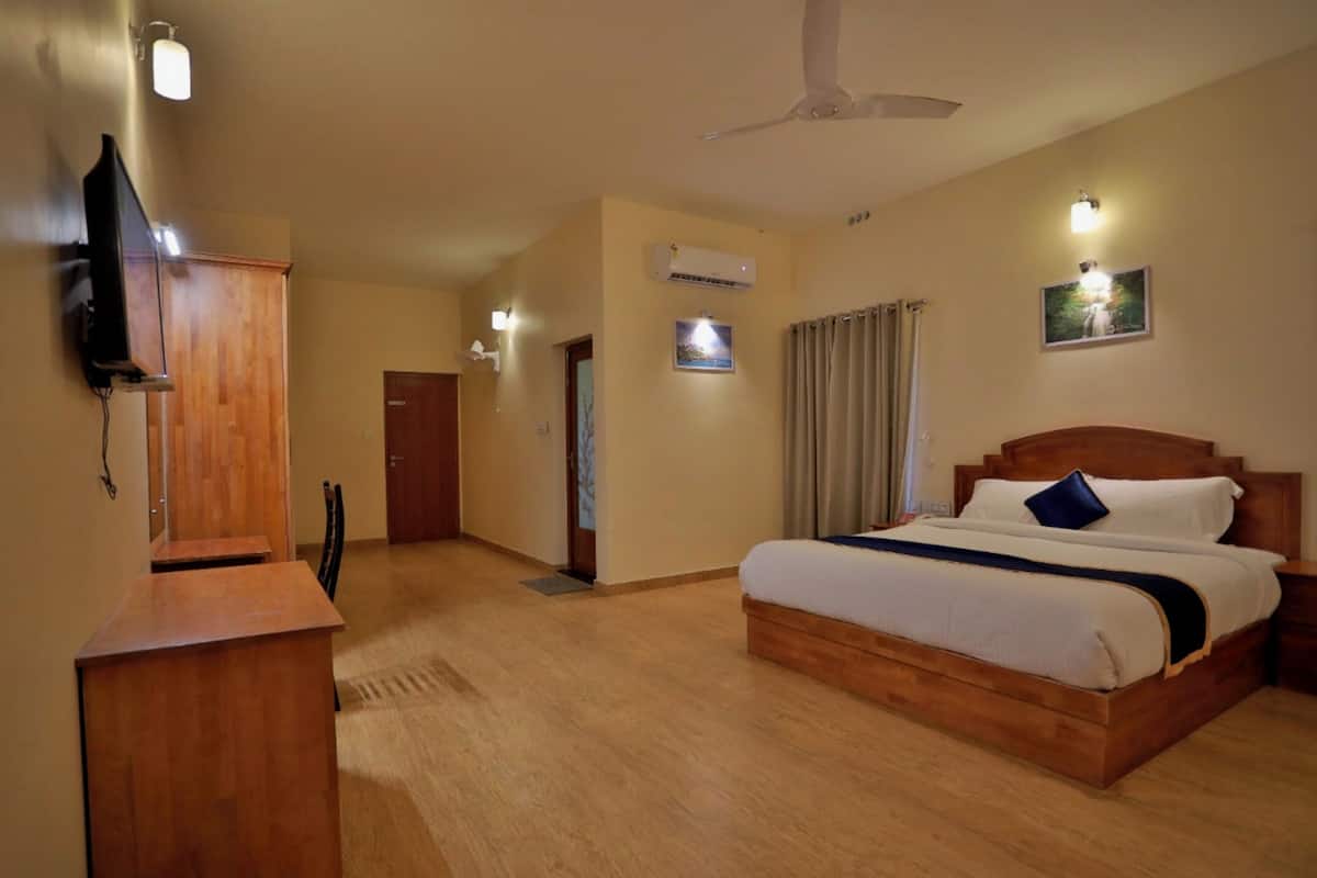 Habitación de hotel con cama de madera, un escritorio, televisor y ventilador de techo.