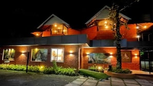 Un edificio de dos pisos con fachada de ladrillo, ventanas iluminadas e iluminación exterior.