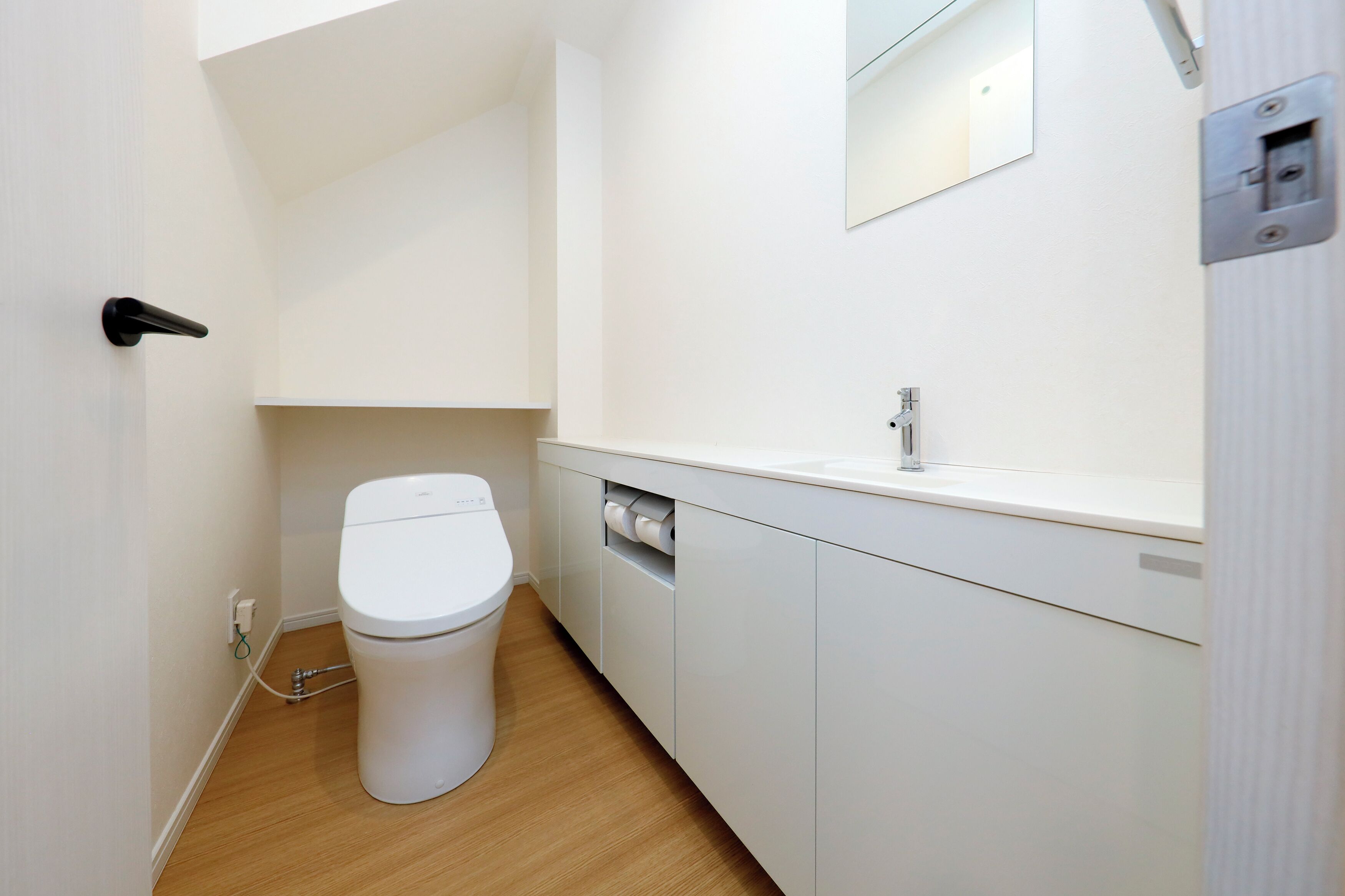 A modern bathroom with a toilet, sink, and cabinet.
