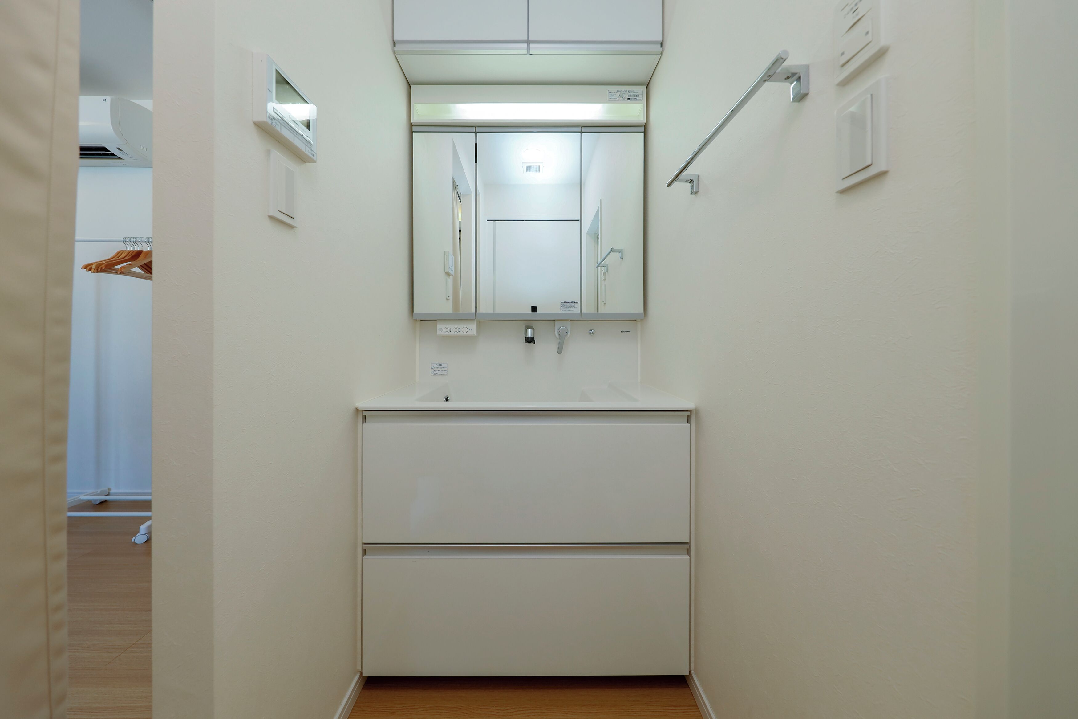 A small, clean bathroom with a mirror, sink, and towel rack.