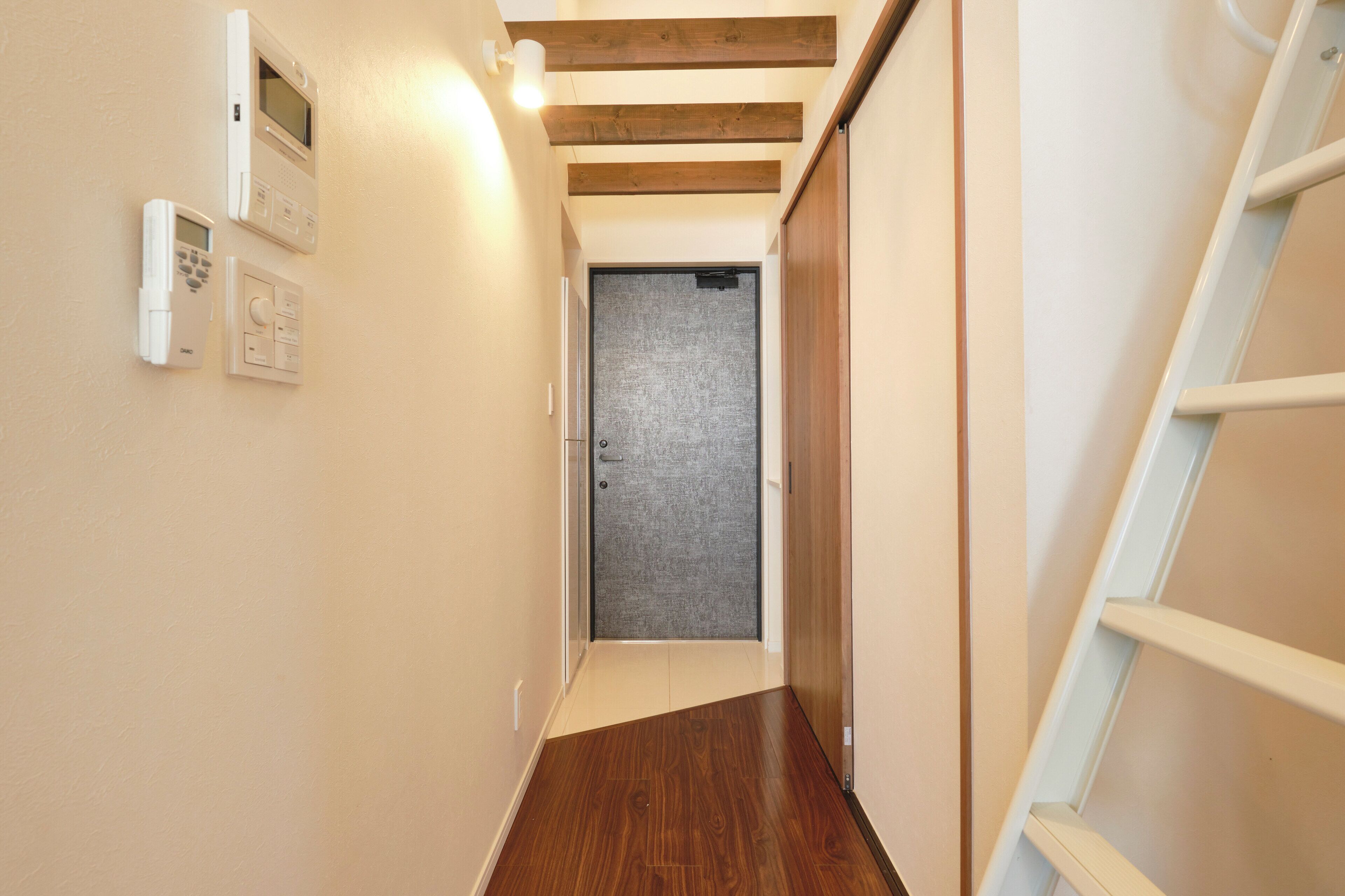 Un pasillo estrecho con suelo de madera y una puerta al final.