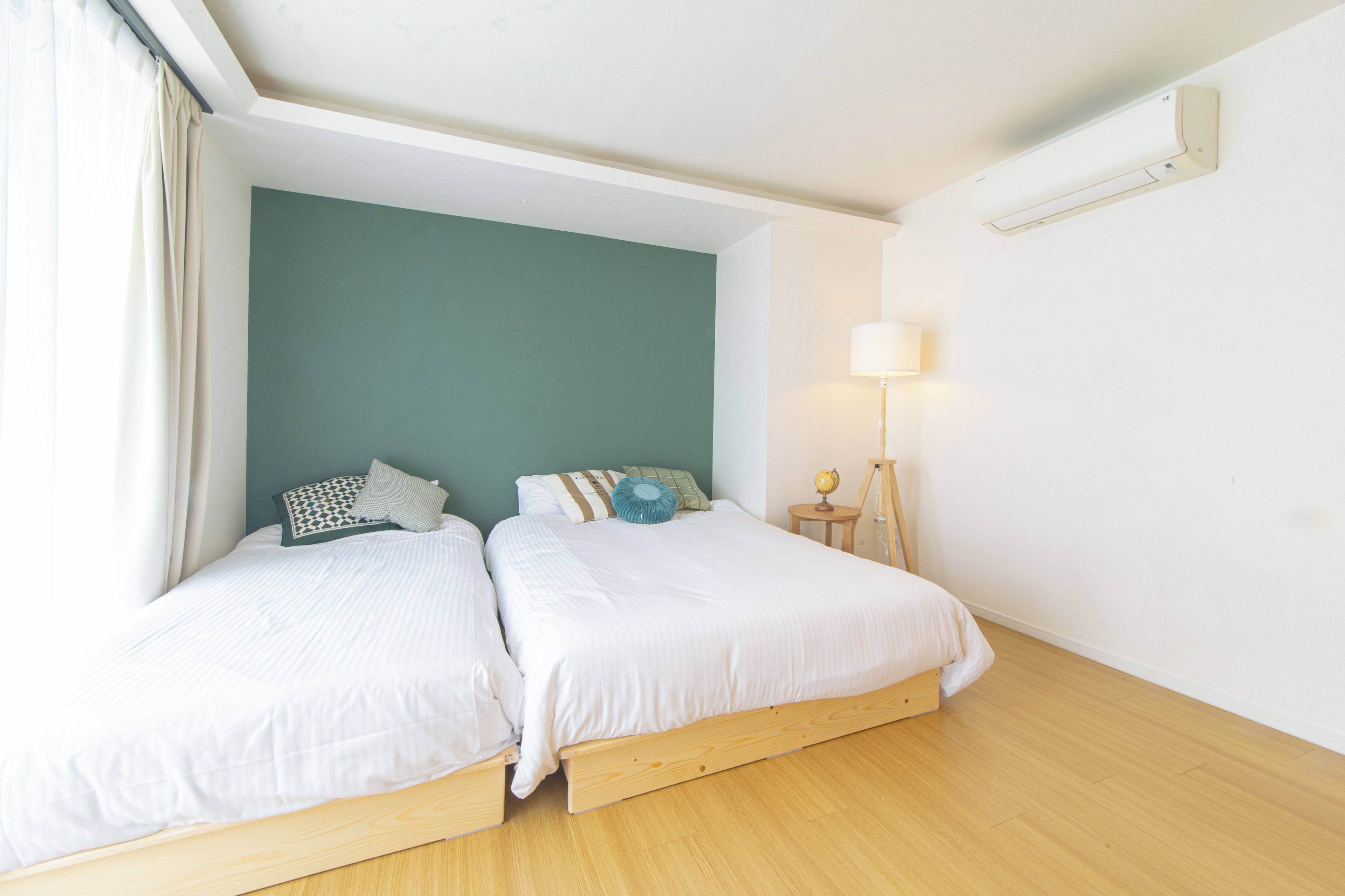 A room with two beds, a lamp, and a globe on a side table.