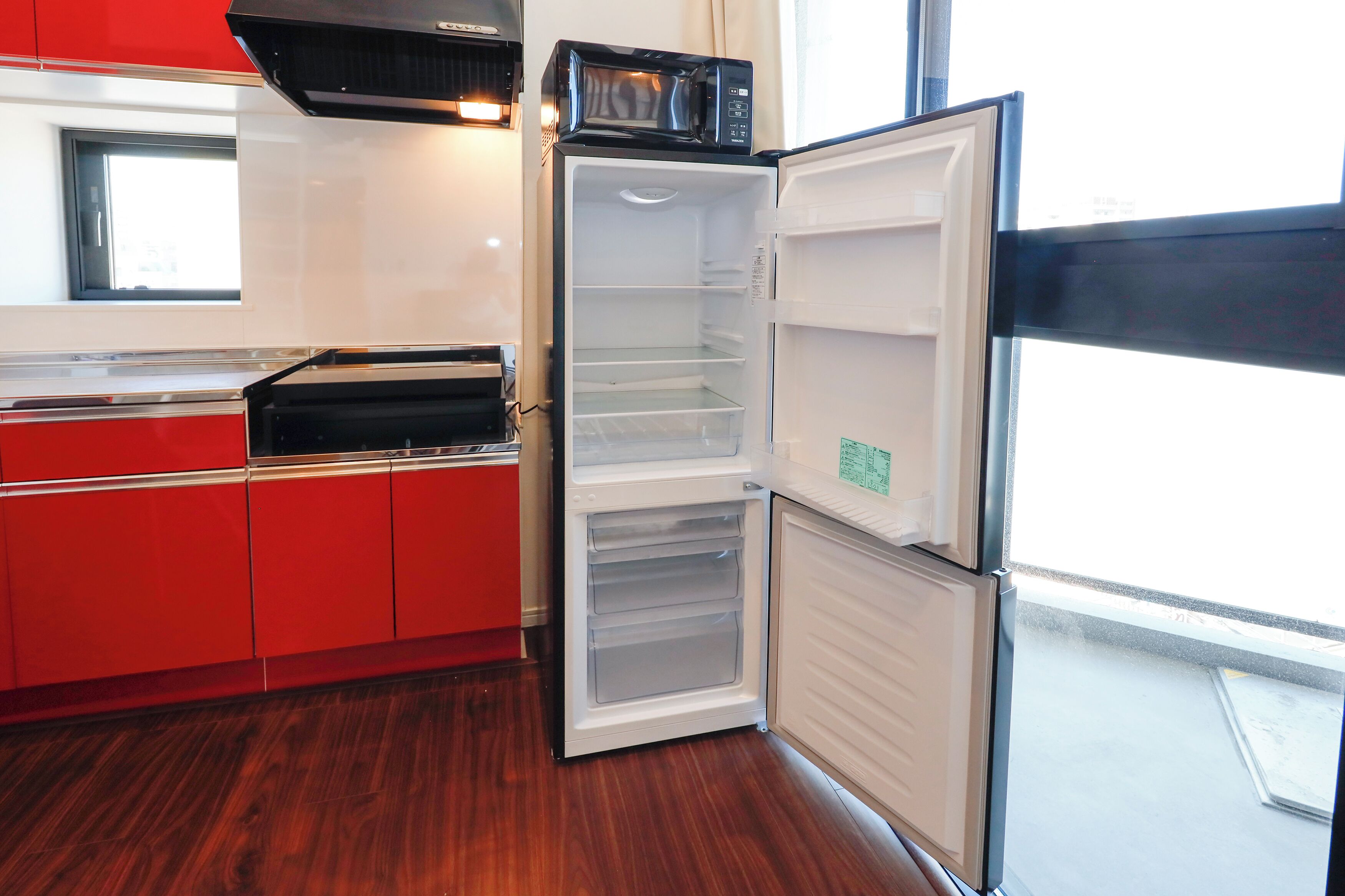 Una cucina con forno a microonde integrato, cappa aspirante in acciaio inossidabile e piano di lavoro rosso.