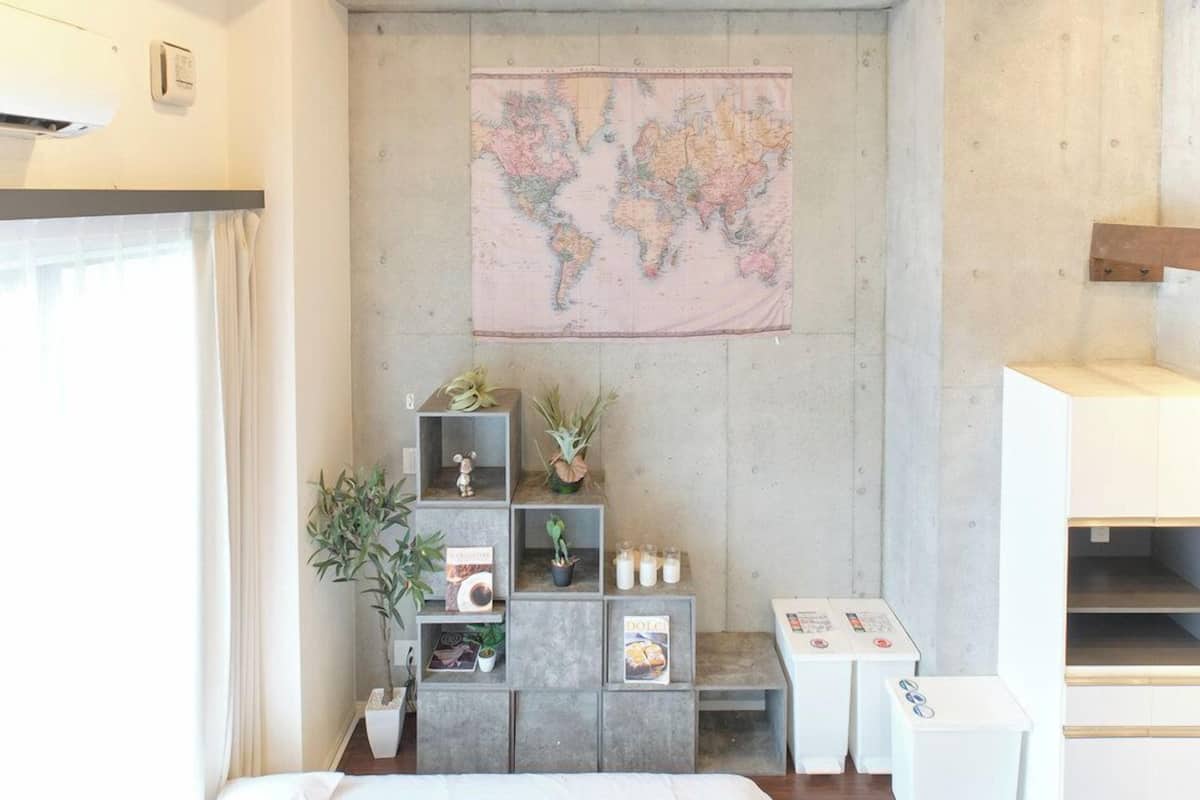 A bedroom with a bed, a ceiling fan, a map on the wall, and a small desk with a chair.