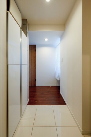 A narrow hallway with a wooden floor, white walls, and a white door at the end. - Kiyosumi SOHO by Tranova (Tokyo)