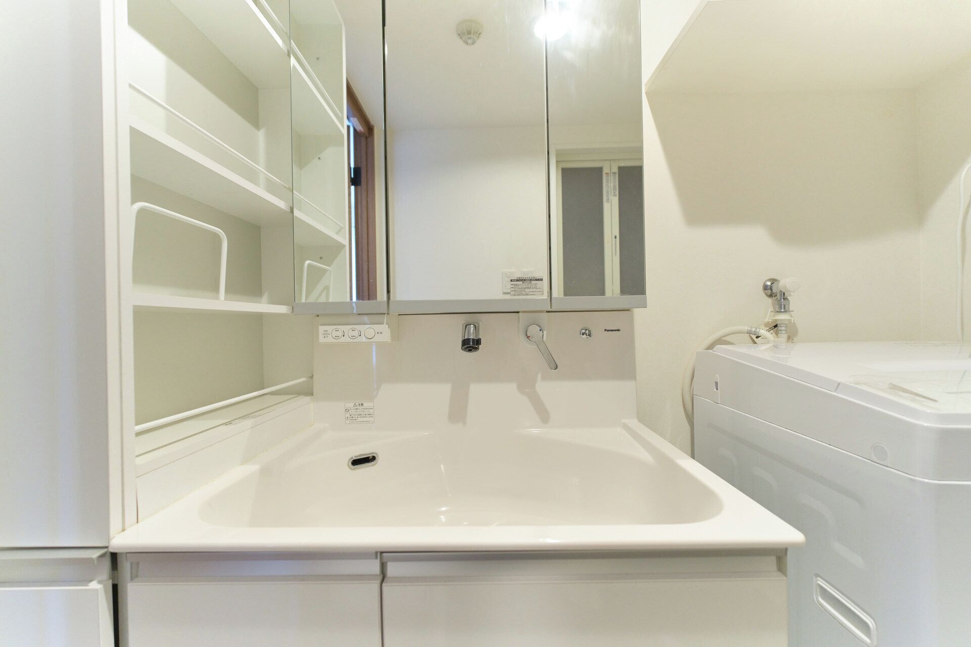 Une salle de bain avec un lavabo blanc, un miroir, des toilettes et un meuble de rangement.